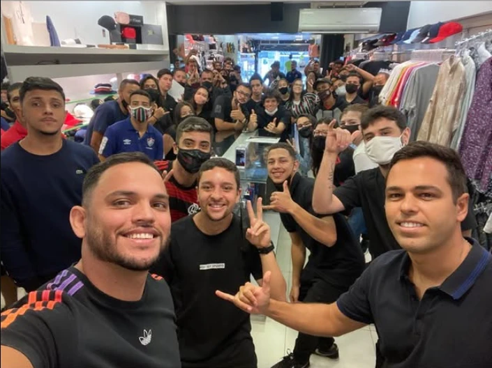 Kaio Costa em selfie com uma equipe grande de vendedores dentro de uma loja
